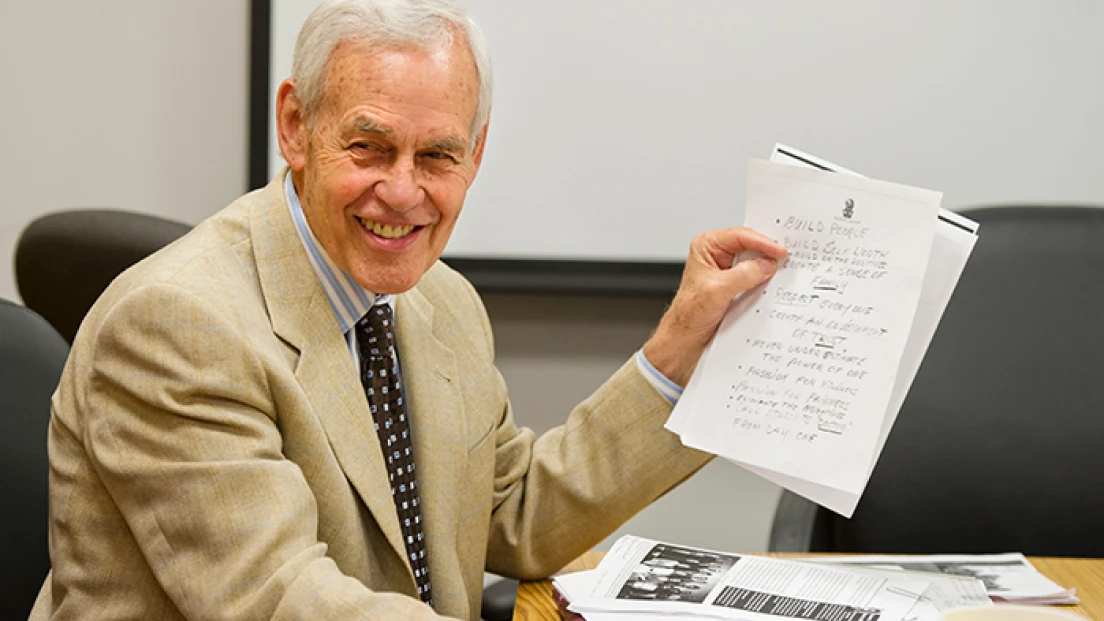 Feature photo of dentist Dr. Moody Alexander at a conference table holding written notes.