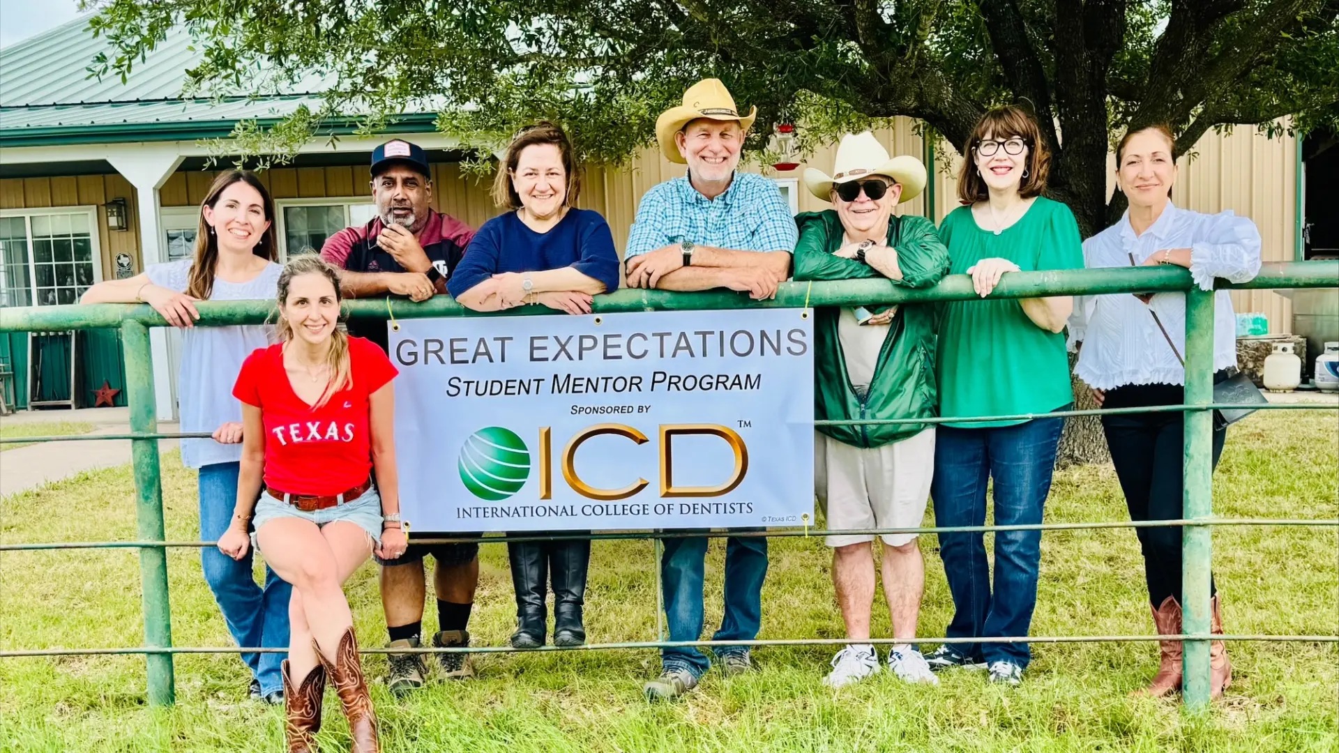 Texas A&M Dentistry faculty members standing behind a pipe rail fence at a ranch.
