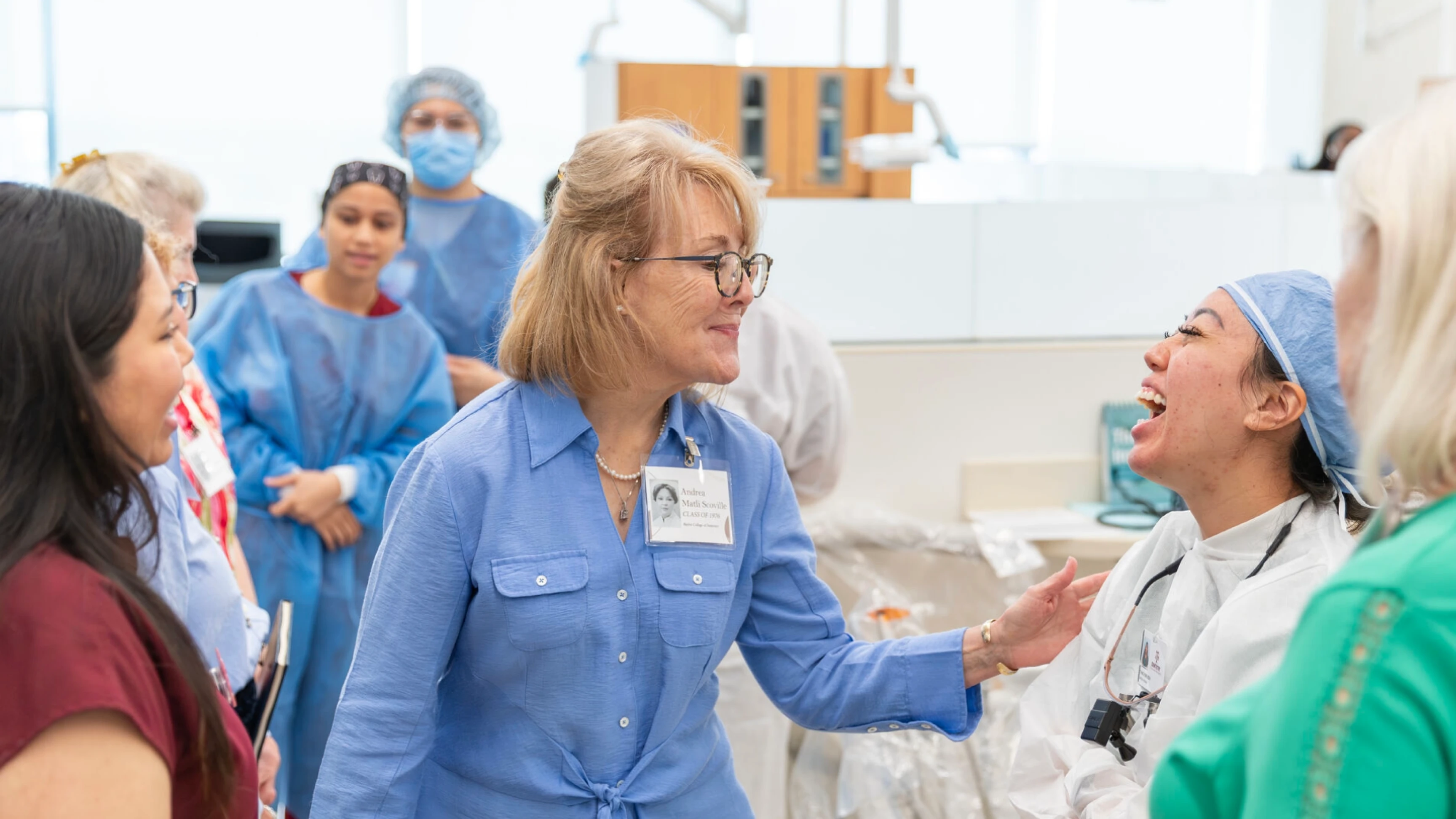 Dental hygiene school alumni laugh with a current student during a reunion tour of campus. 
