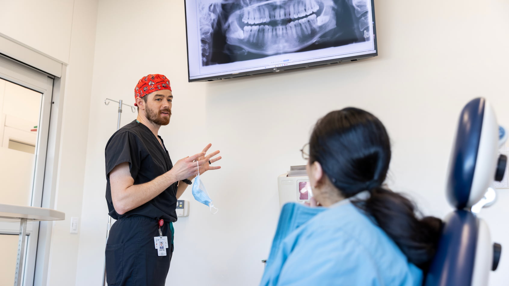 A dental provider discusses a panoramic X-ray with a patient in a clinical setting.