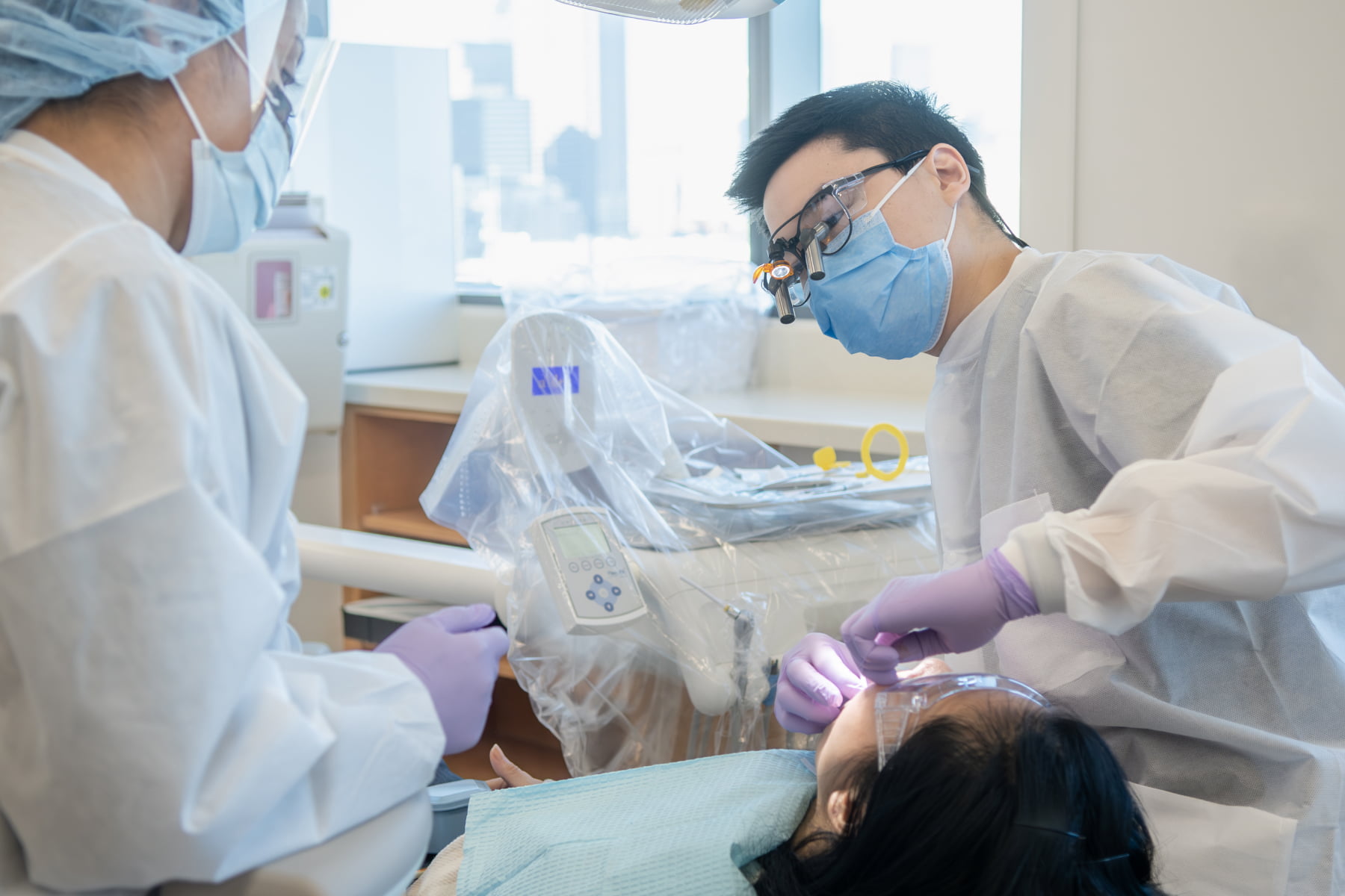 Two dental providers treat a patient in a dental clinic.