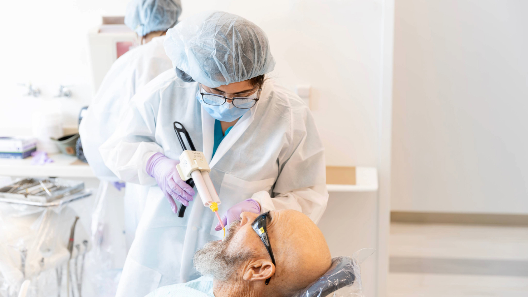 A dental student performs a procedure on a patient in a dental clinic.