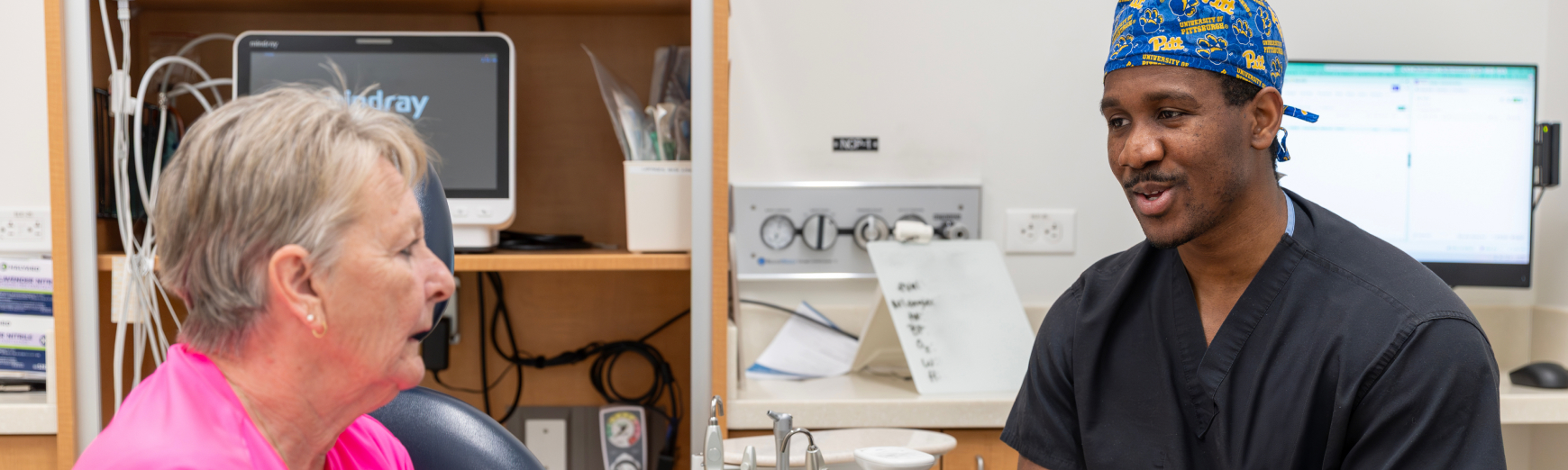 An oral surgery resident or practitioner consulting with a patient in a dental clinic setting.