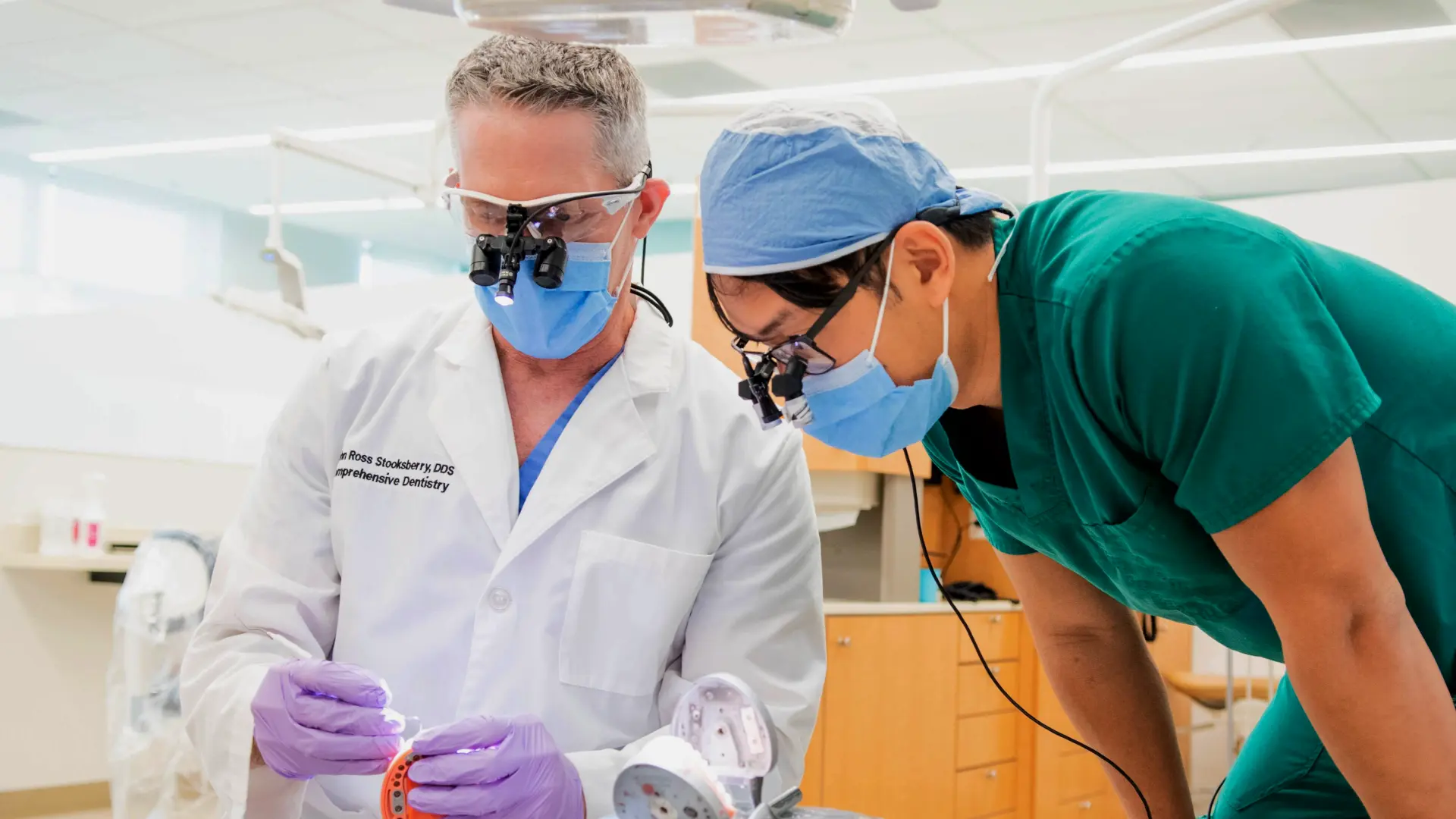 Faculty dentist instructing a student dentist in clinic.