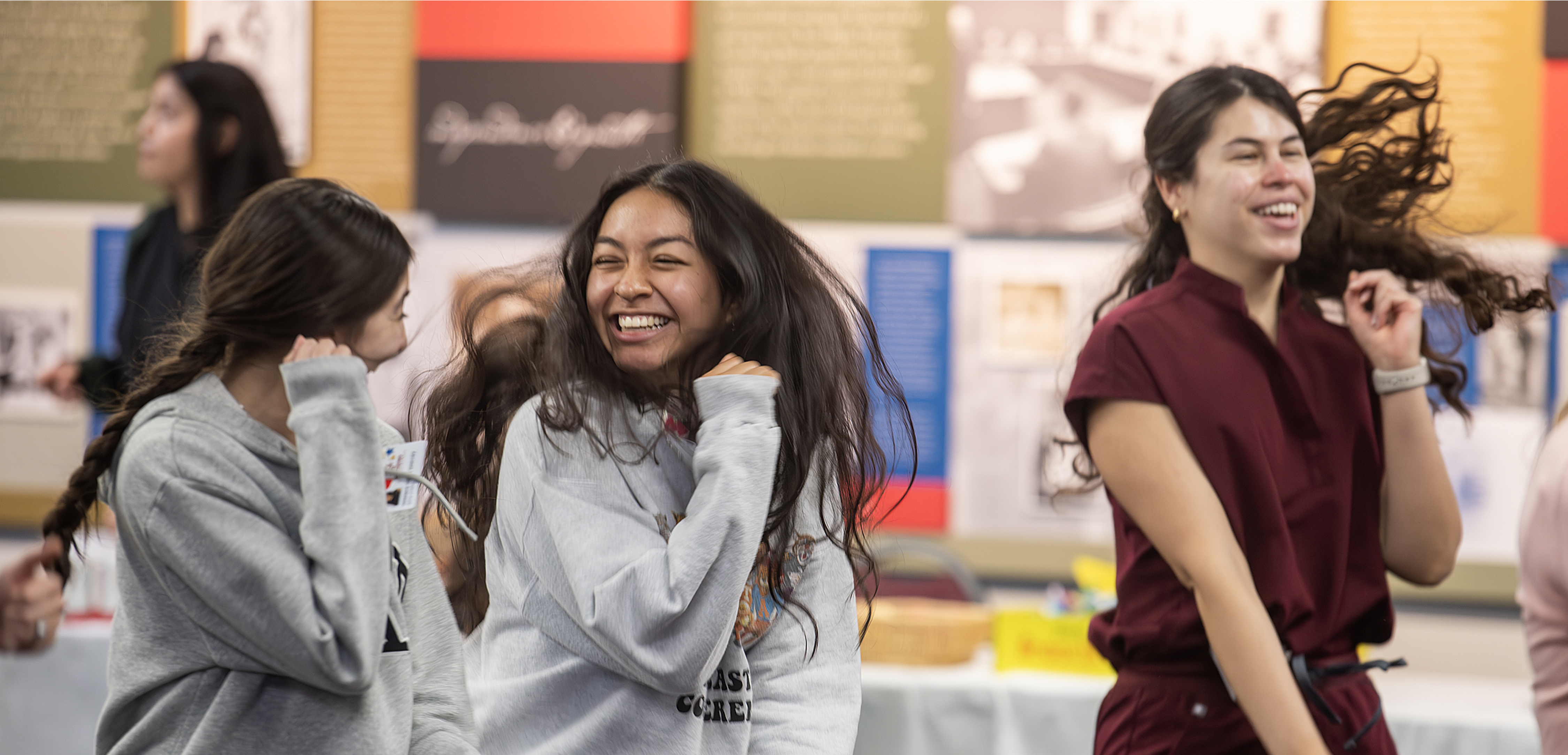 A wide banner featuring a group of dental students laughing and celebrating together enthusiastically during a campus event.