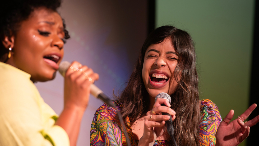 Two dental students performing together with microphones on stage during a student organization talent show or event.