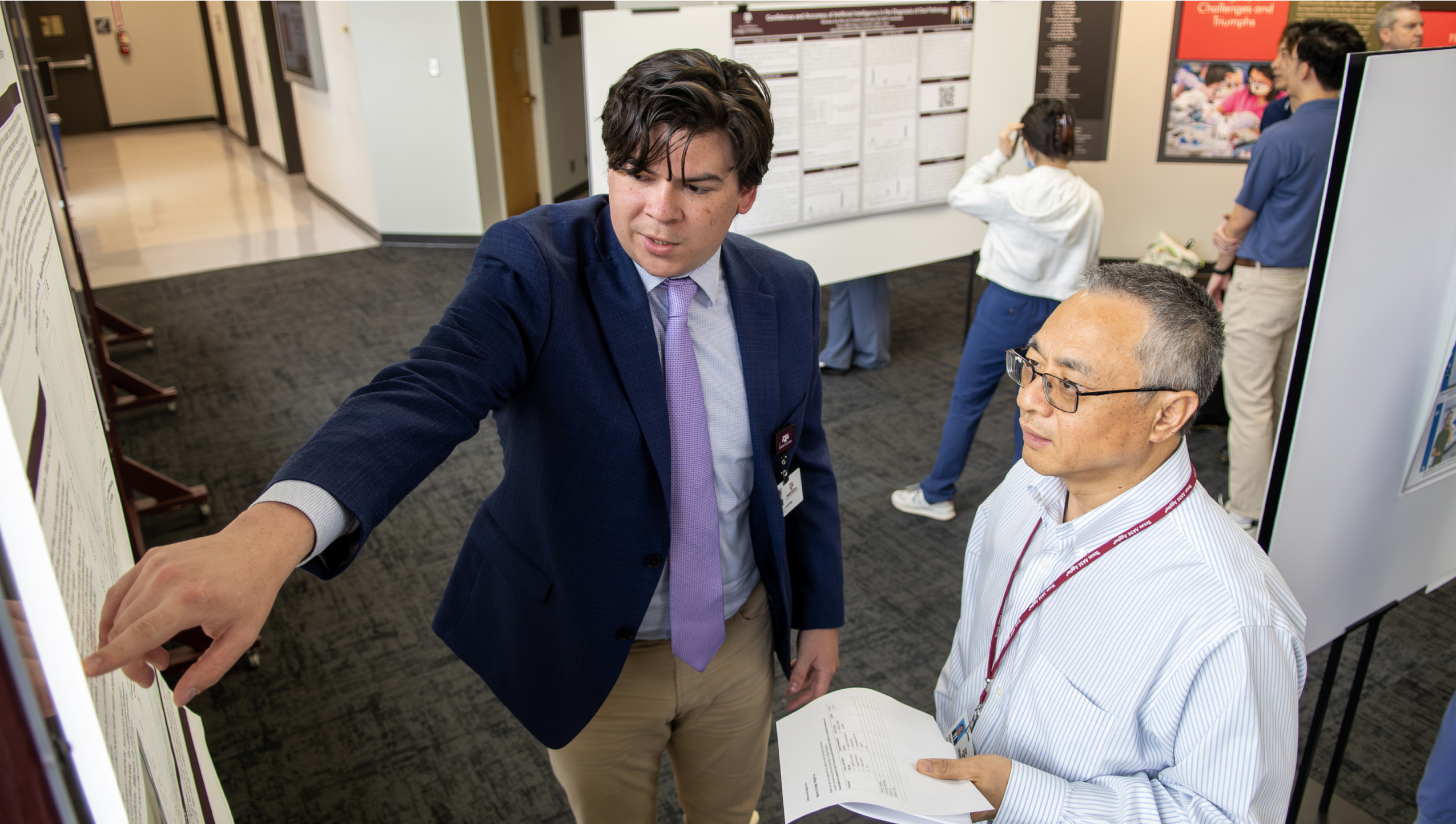A student presents research findings to a faculty member at a poster session.